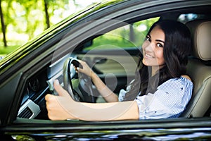 Happy brunette woman inside a car driving in the street and gesturing thumb up