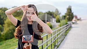 Happy brunette woman making photo with retro camera on city street