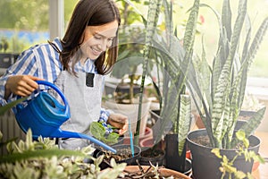 Happy brunette woman pouring fresh water on potted plants cultivated growing domestic garden