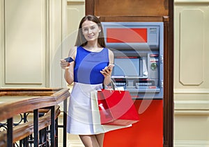 Happy brunette woman withdrawing money from credit card at ATM photo