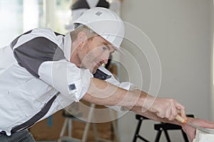 Happy builder in hardhat plastering wall