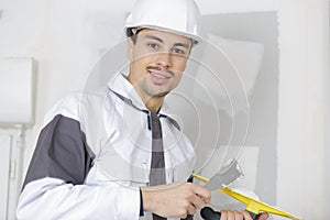 Happy builder in hardhat plastering wall