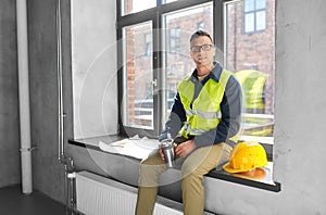 happy builder with tumbler sitting on window sill