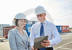 Happy builders in hardhats with tablet pc outdoors