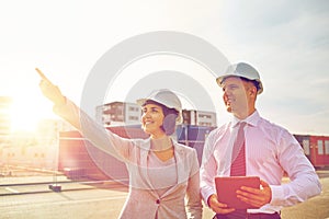 Happy builders in hardhats with tablet pc outdoors