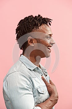 The happy business Afro-American man standing and smiling against pink background. Profile view.