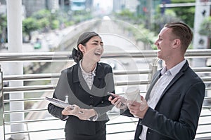 Happy Business colleagues walking outside office & talking to each other.