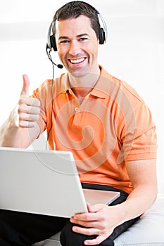 Happy business male on laptop with headset on smiling