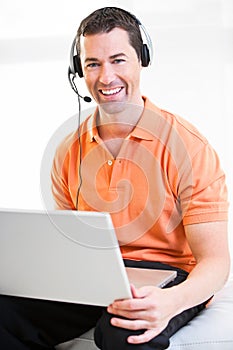 Happy business male on laptop with headset on smiling