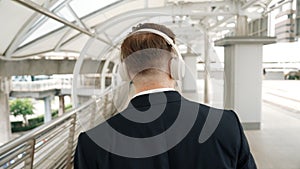 Happy business man dancing while wear headphone at bridge. Back view. Urbane.