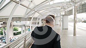 Happy business man dancing while wear headphone at bridge. Back view. Urbane.