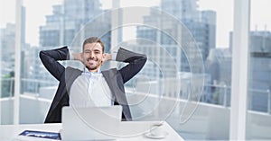 Happy business man at a desk sitting against city background