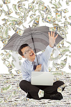 Happy business man holding a umbrella and catching money