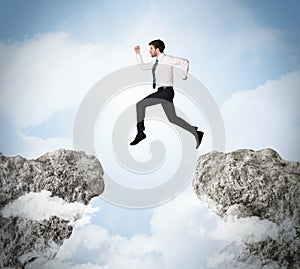 Happy business man jumping over a cliff