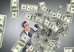 Happy business man looking at money rain against grey background