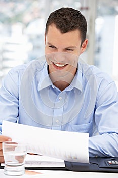 Happy Business Man Reading Notes in Office