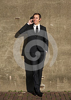 Happy business man relaxing outdoors with mobile phone