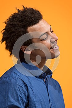 The happy business man standing and smiling against orange background.