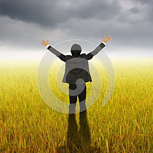 Happy Business Man standing in Yellow rice field and Rainclouds photo