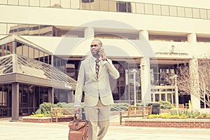 Happy business man talking on his phone while walking outside