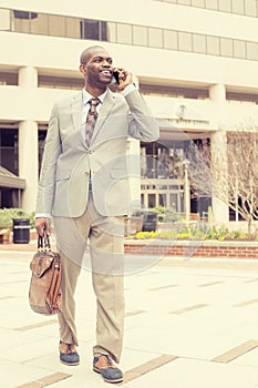 Happy business man talking on his phone while walking outside