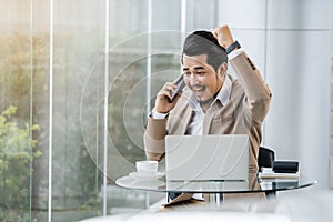 Happy business man talking on mobile phone and using laptop