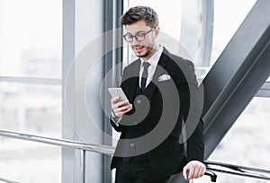 Happy business man texting on smart phone in airport