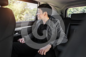 Happy business man thinking and looking view out of window while sitting in the back seat of car