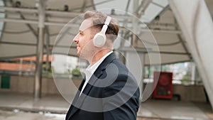 Happy business man using headphone listening relax music and move along. Urbane.