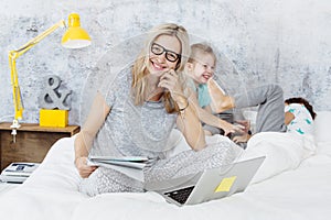 Happy business mum at work while her kids are playing in bed photo