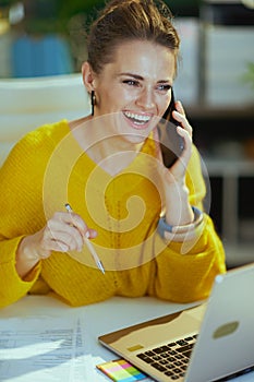 Happy business owner woman in green office talking on phone