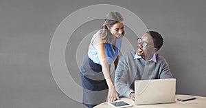 Happy business people at a desk using a computer against grey background