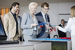 Happy business people with files at reception counter in convention center