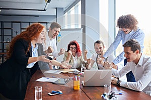 Happy business people gathered around table in office