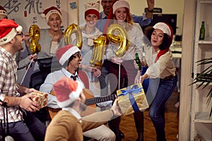 Happy business people have fun and dancing in Santa hat at Xmas party