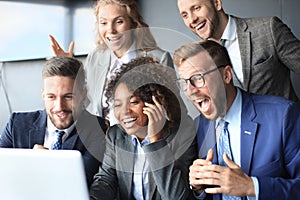 Happy business people laugh near laptop in the office. Successful team coworkers joke and have fun together at work.