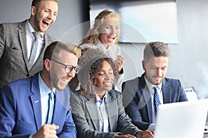 Happy business people laugh near laptop in the office. Successful team coworkers joke and have fun together at work.