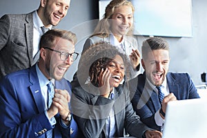 Happy business people laugh near laptop in the office. Successful team coworkers joke and have fun together at work.