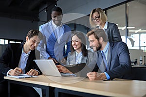 Happy business people laugh near laptop in the office. Successful team coworkers joke and have fun together at work.