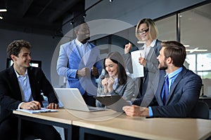 Happy business people laugh near laptop in the office. Successful team coworkers joke and have fun together at work.