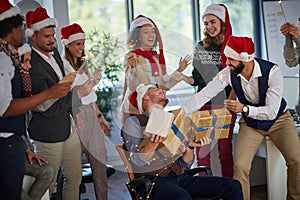 Happy business people in santa hat with Christmas present at company party