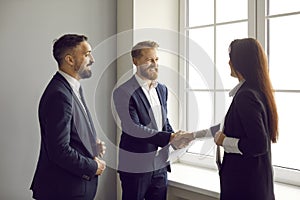 Happy business people shake hands in agreement and end successful meeting in office.