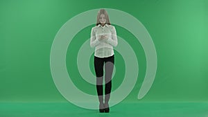 Happy business woman is chating on her phone standing front on the green screen