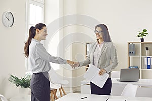Happy business woman and client smiling and shaking hands confirming business deal