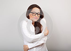 Happy business woman in eye glasses hugging herself with natural emotional enjoying face with closed eyes on studio blue