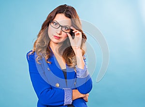 Happy business woman in eyeglasses looking at the camera over blue background