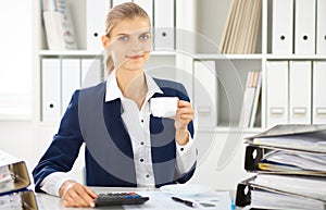 Happy business woman or female accountant having some minutes for coffee and pleasure at working place