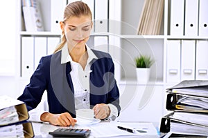 Happy business woman or female accountant having some minutes for coffee and pleasure at working place