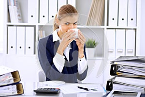 Happy business woman or female accountant having some minutes for coffee and pleasure at working place