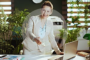 happy business woman in green office giving hand for handshake